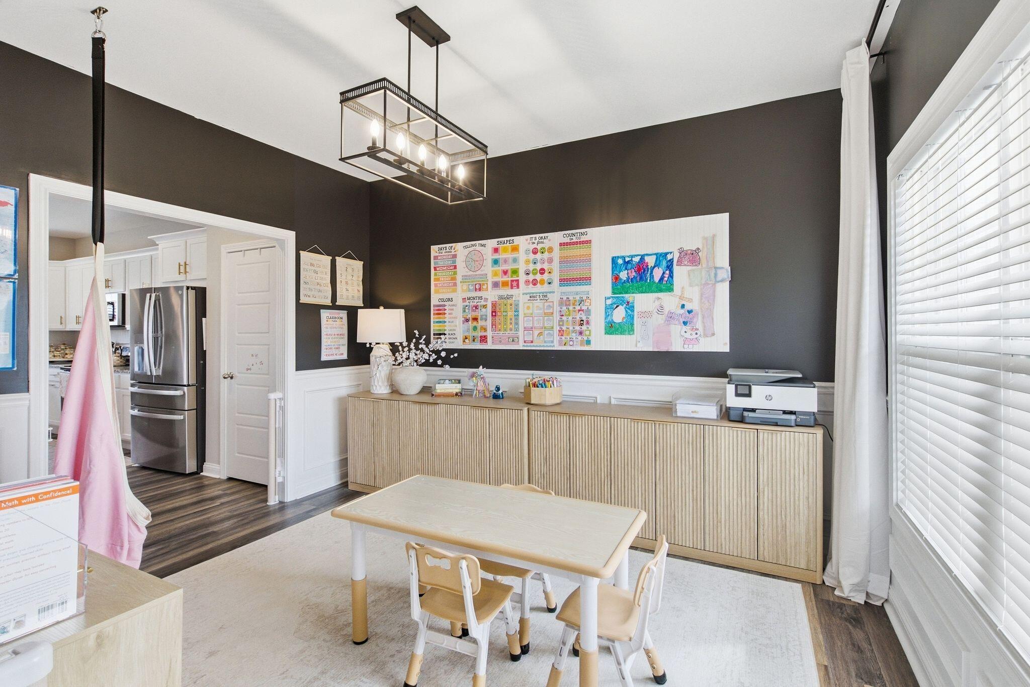 Playroom with a child-sized table, learning charts, and a long fluted storage cabinet.