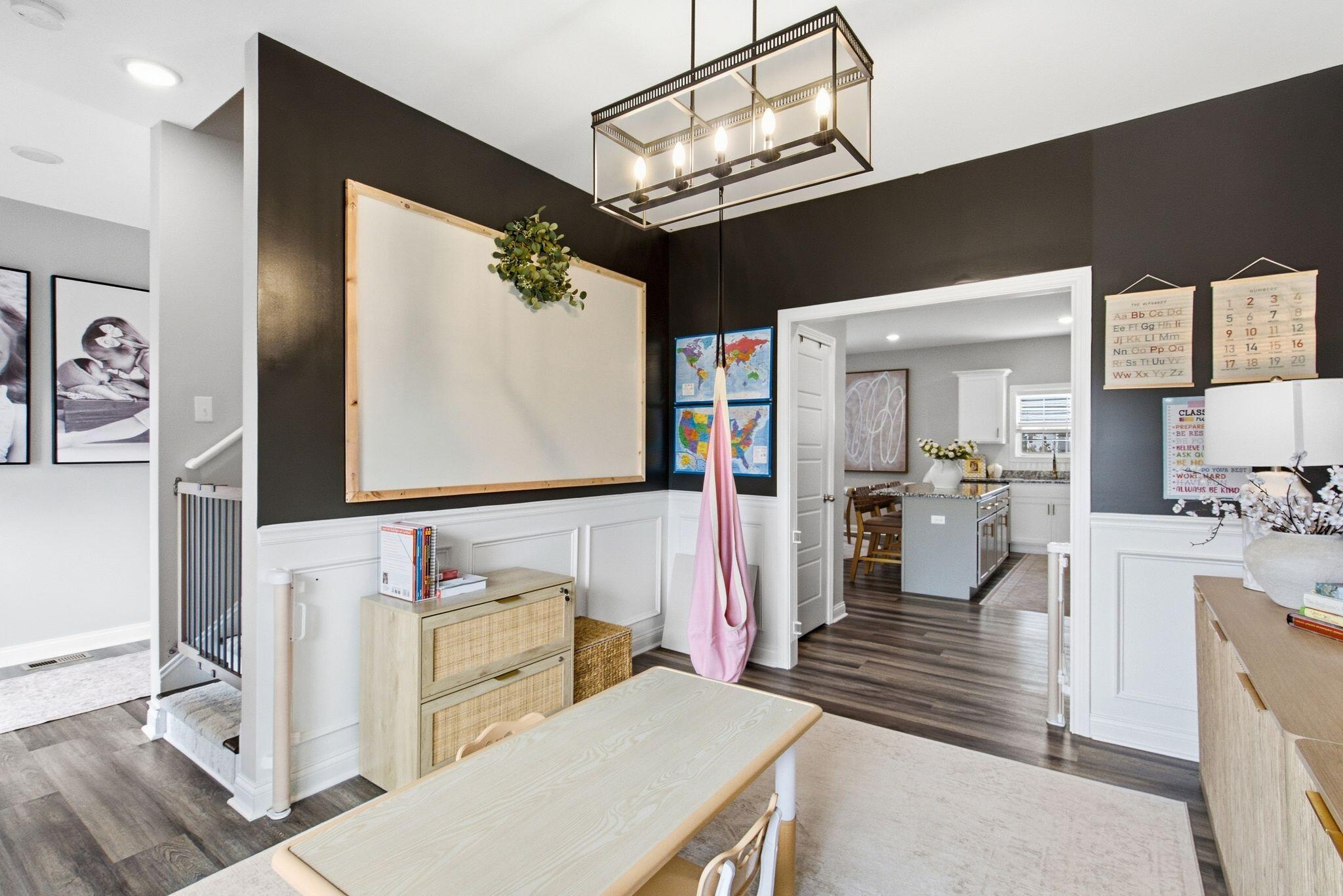 Dining and study area with a long table, large wall board, and adjoining kitchen.