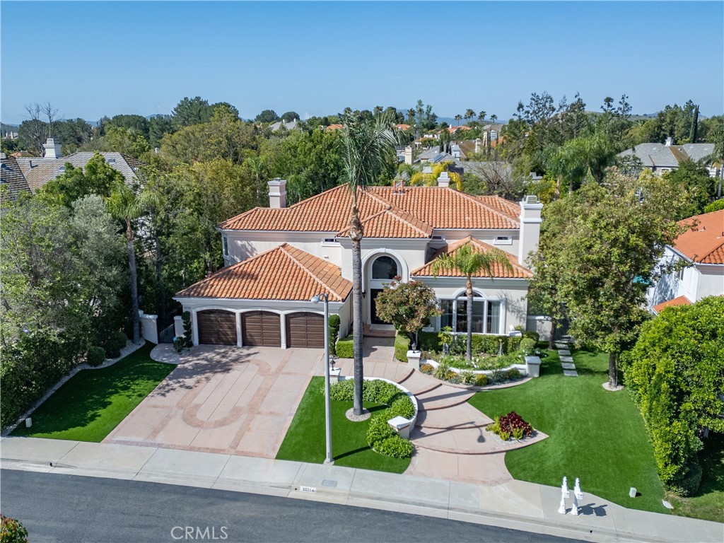 Aerial view of a Mediterranean-style home with terracotta roofs, a three-car garage, and landscaped grounds.