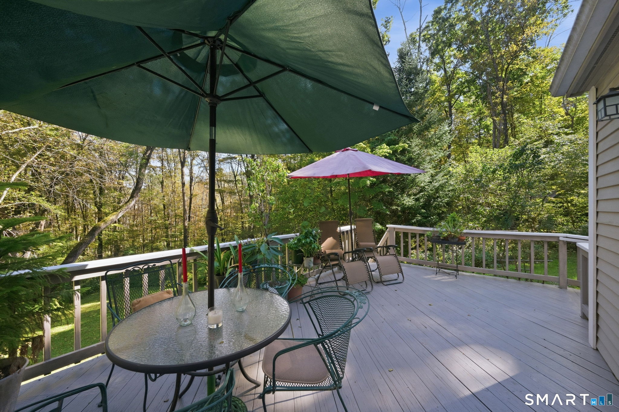 Wooded outdoor deck with patio seating and large shade umbrellas.