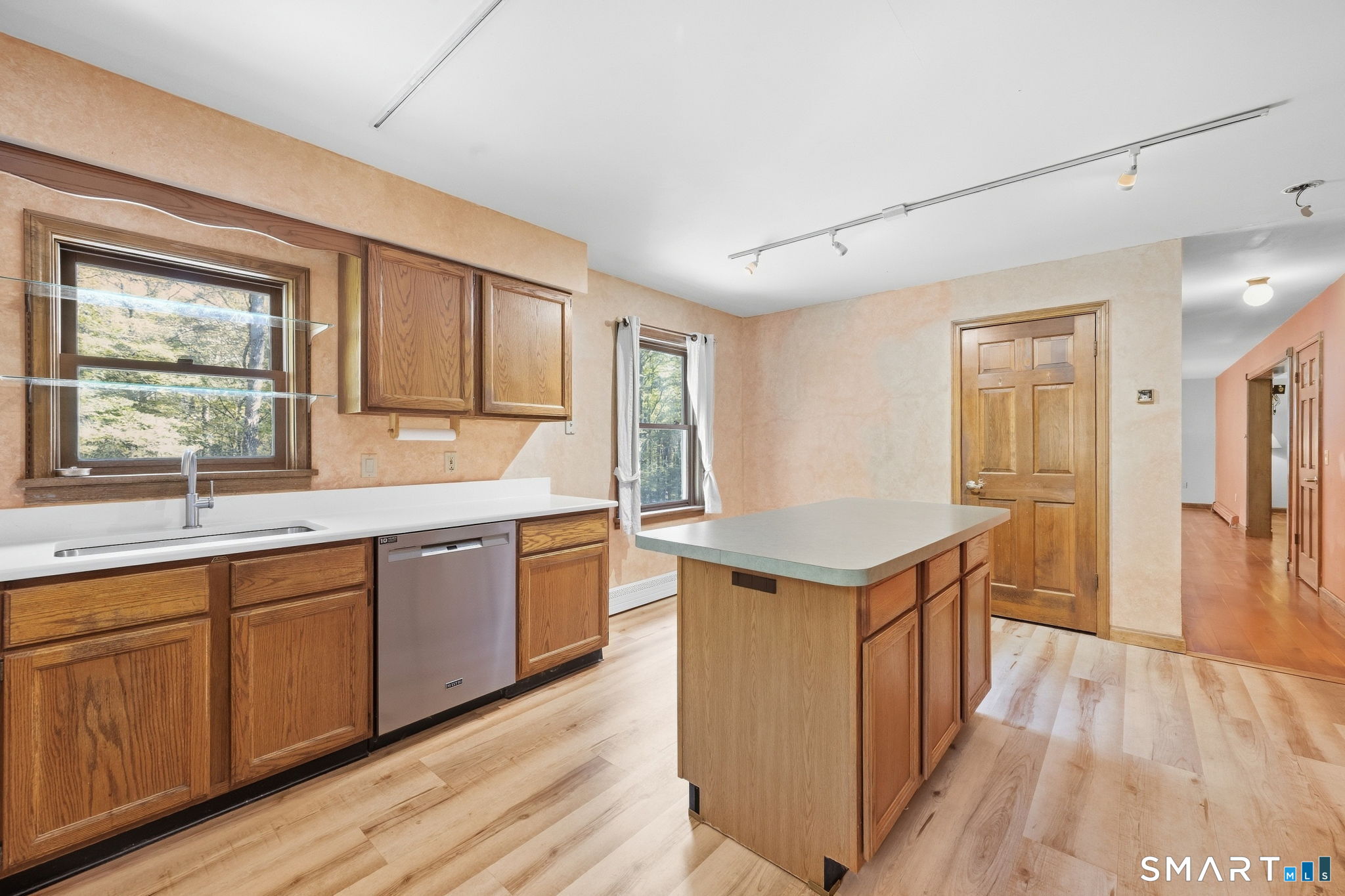 Kitchen with wood cabinets, a large island, white counters, and light wood flooring.