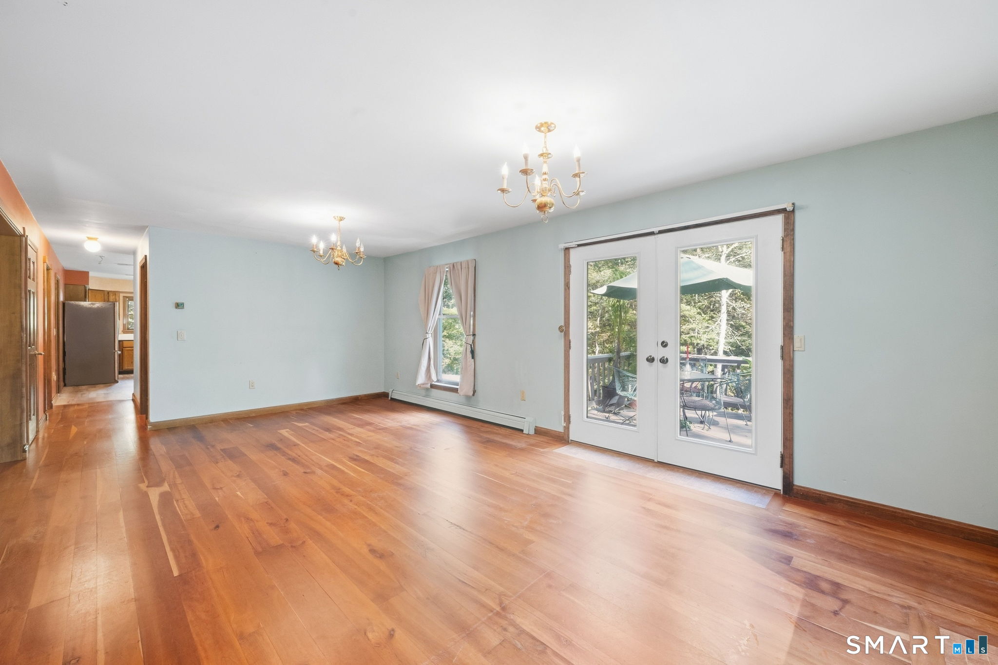 Empty living room with hardwood floors and French doors opening to a deck.