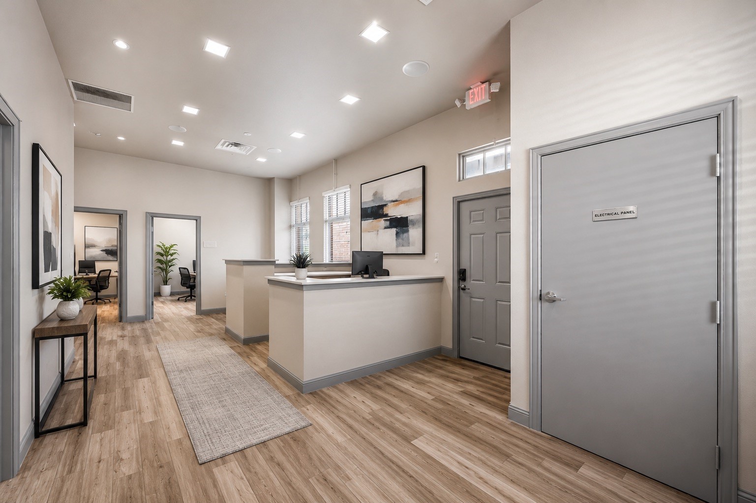 Office reception area with a white desk, two office doorways, and wood-look flooring.