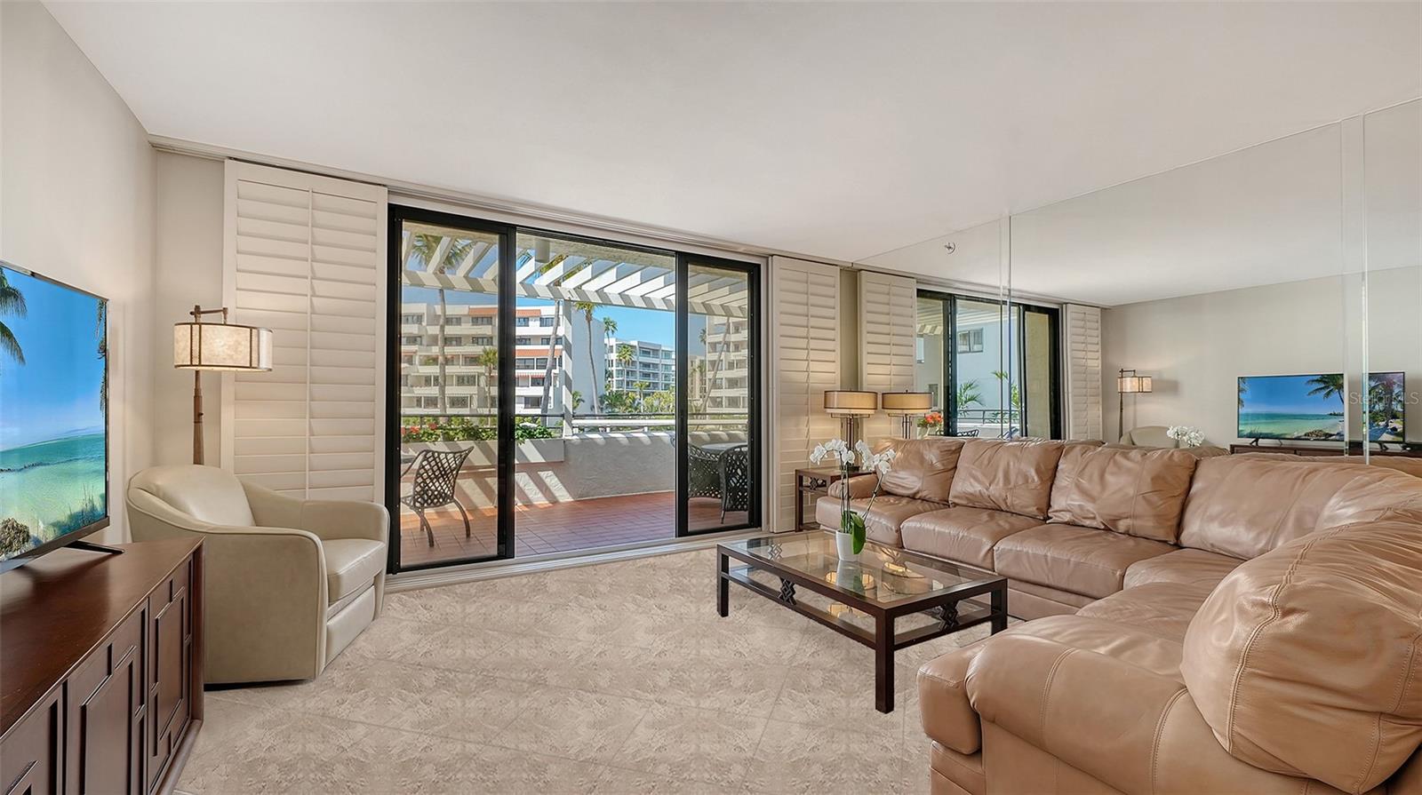 Living room with tan leather seating and sliding glass doors opening to a balcony.