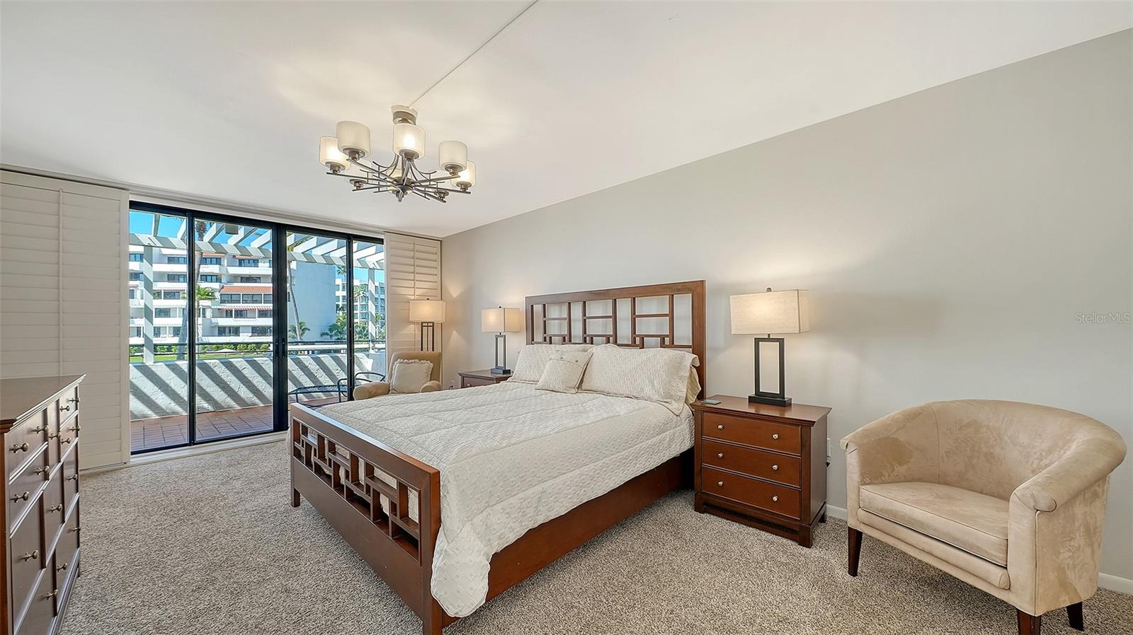 Furnished bedroom with a large wooden bed and sliding glass doors opening to a balcony.