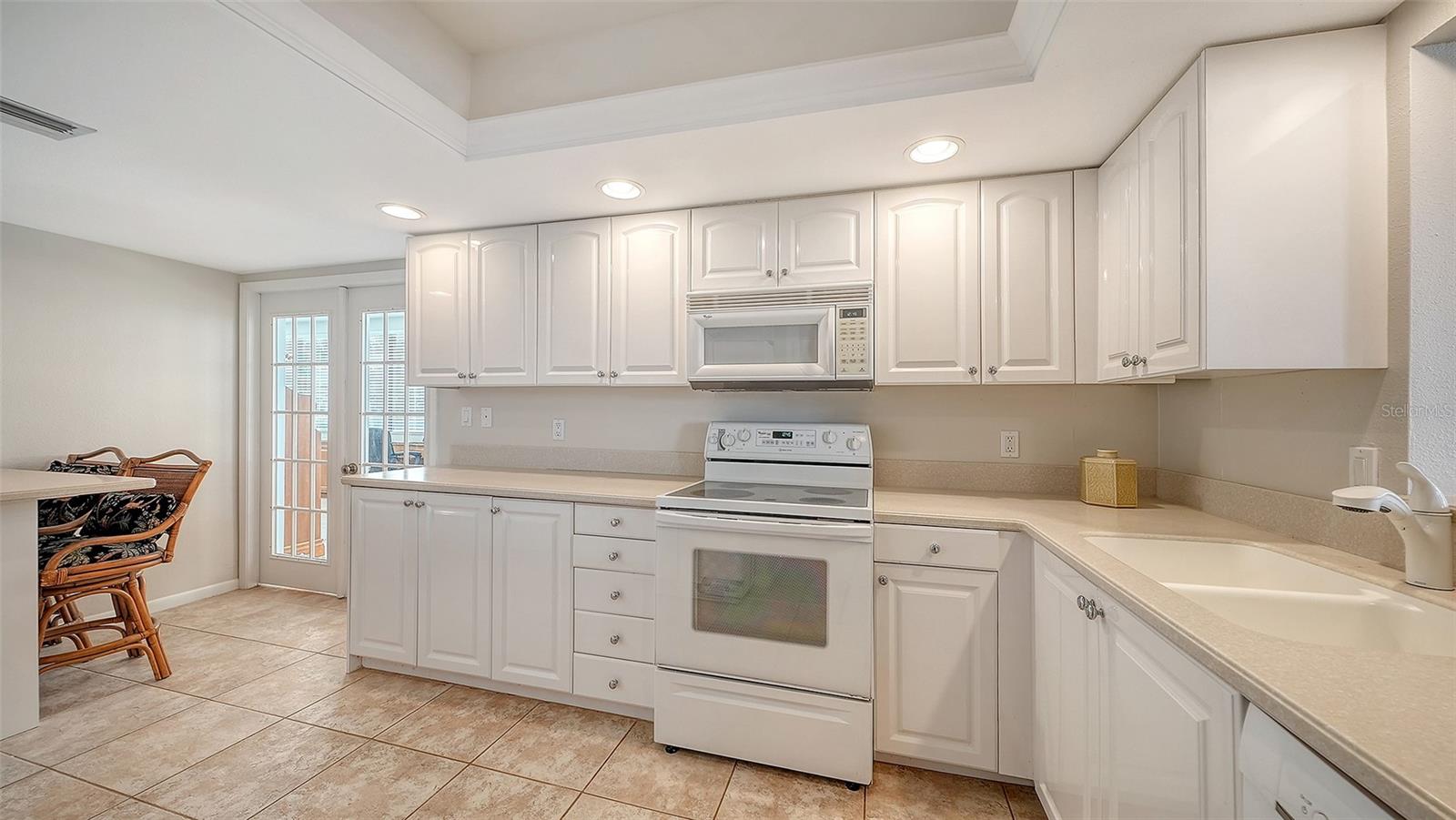Kitchen with white cabinets, tiled floors, and a built-in range and microwave.