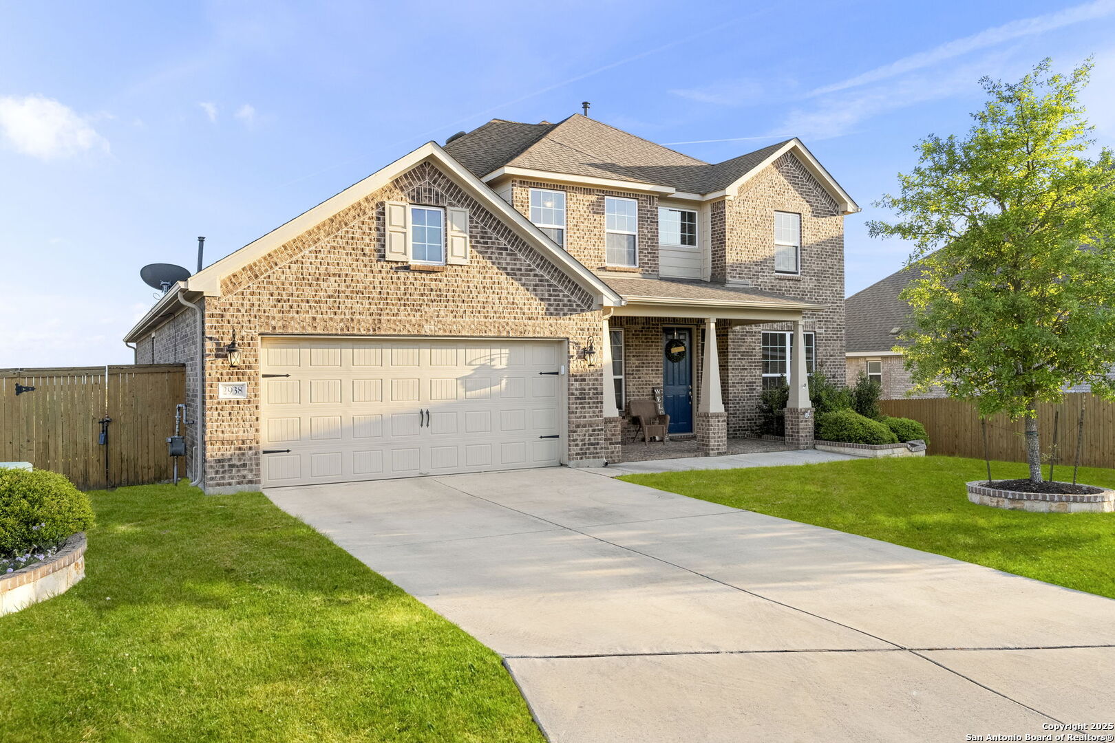 Two-story brick home with a two-car garage, blue front door, and broad driveway.