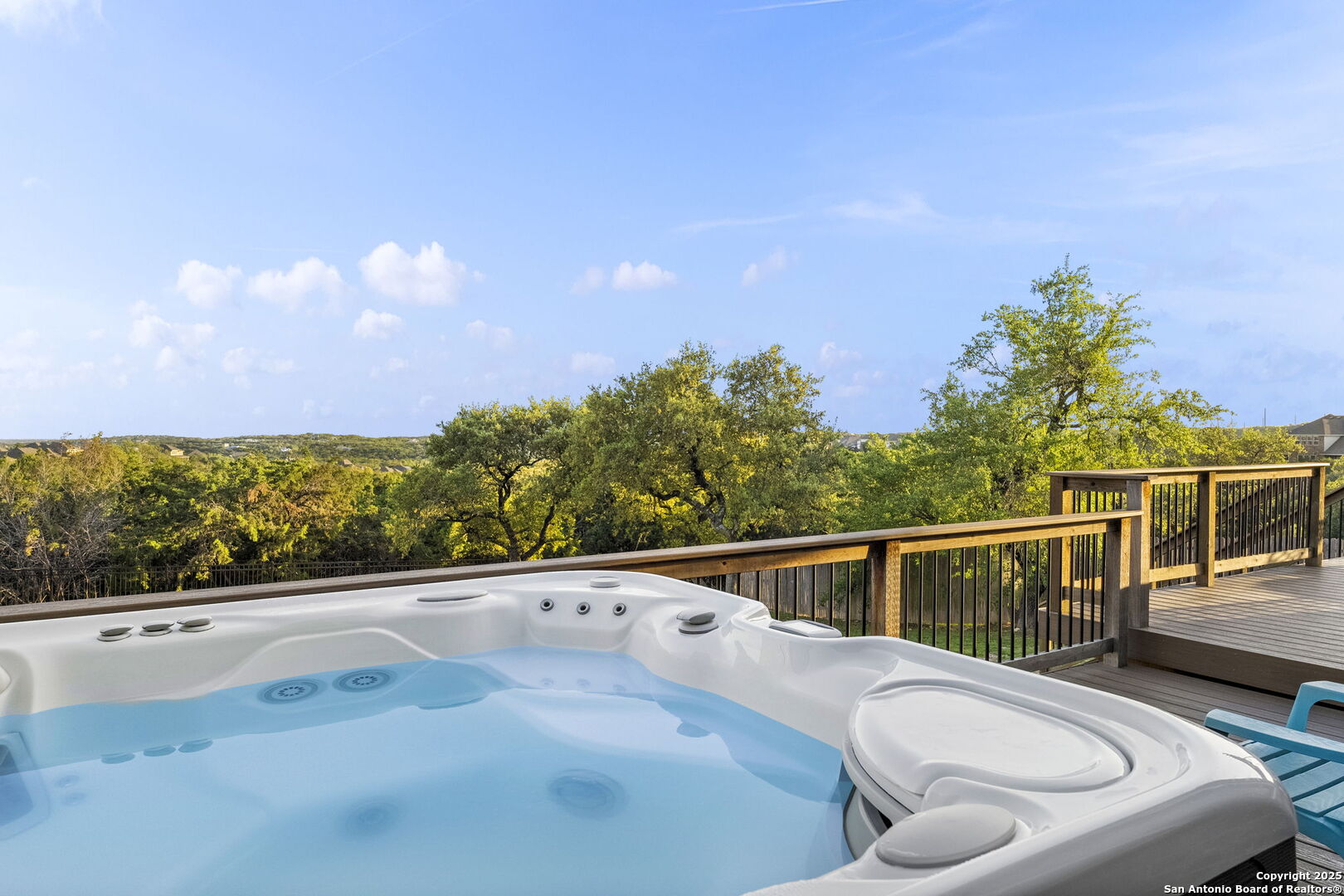 Outdoor hot tub on a wooden deck overlooking trees and rolling hills.