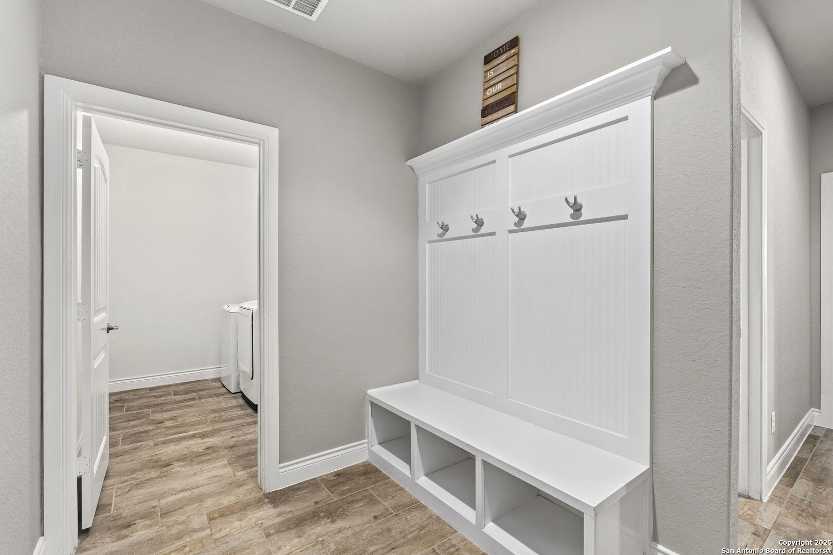 Entryway with a white built-in bench, cubbies, and coat hooks beside a doorway.