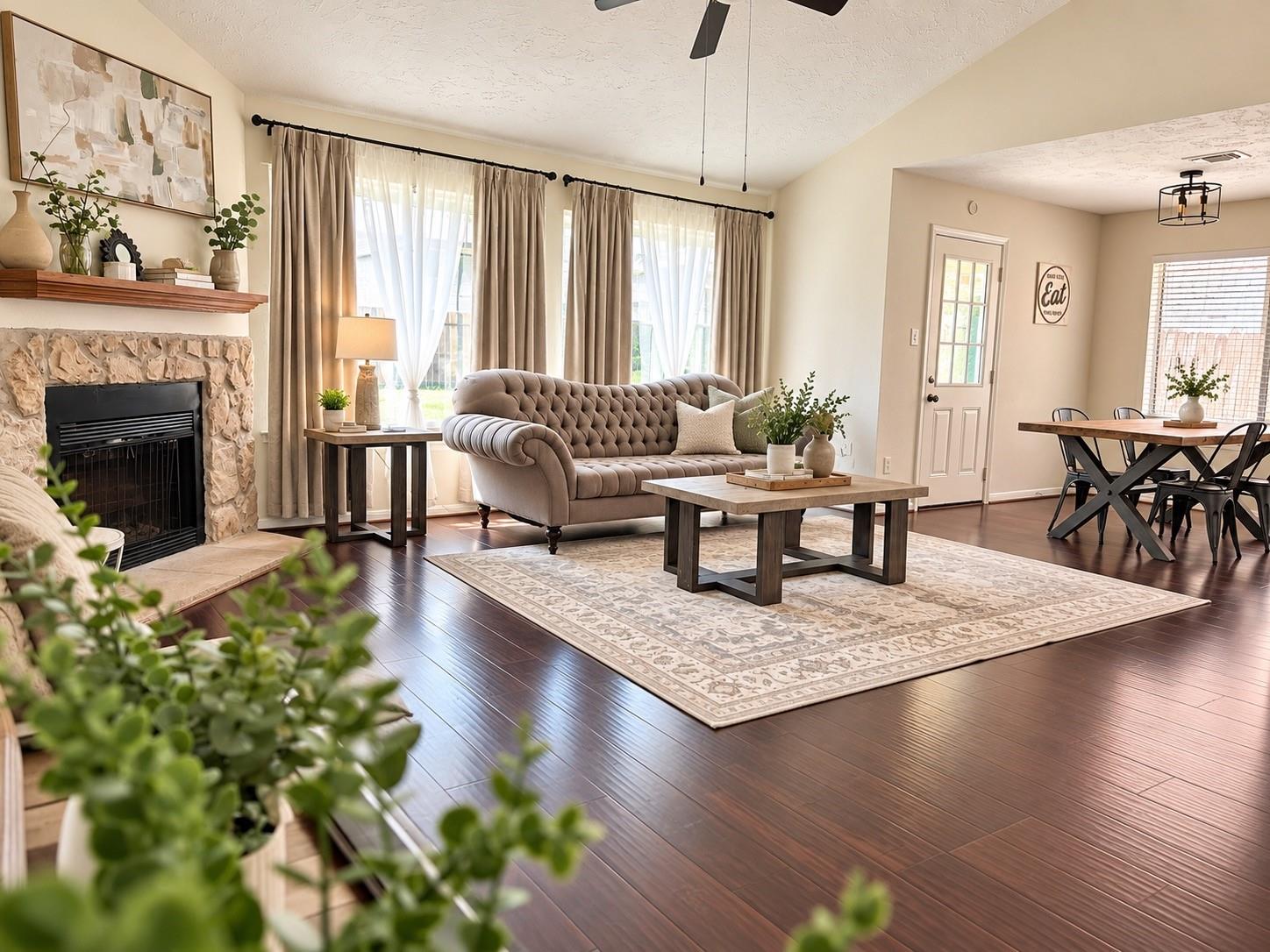 Living room with a stone fireplace, tufted sofa, and adjoining dining area.