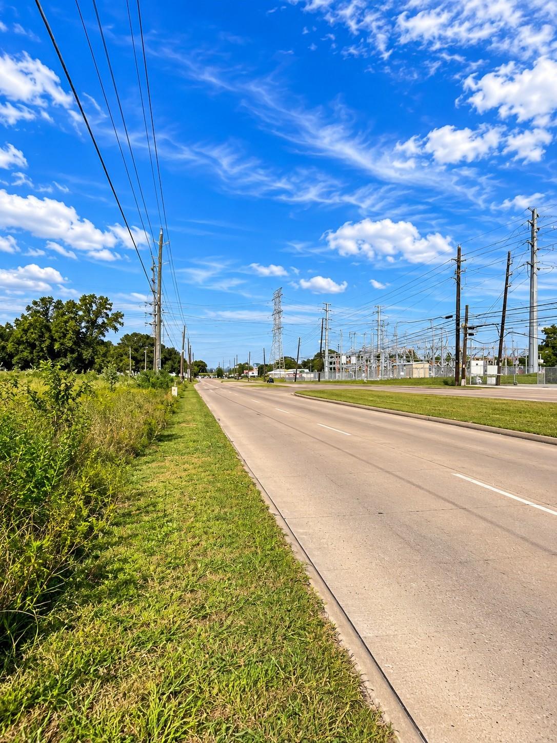Roadside view with a paved road, utility lines, and an electrical substation.