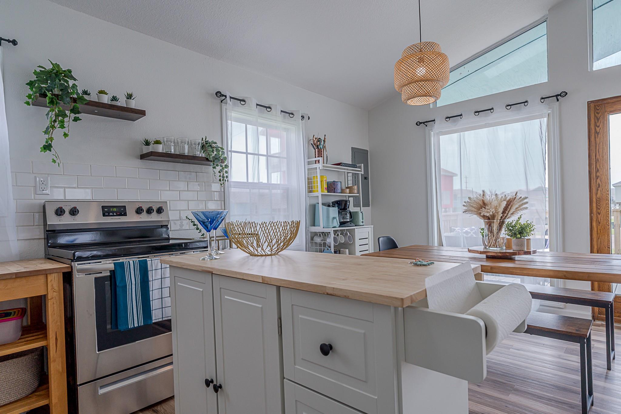 Bright kitchen with a white island, stainless steel range, subway tile backsplash, and adjoining dining area.