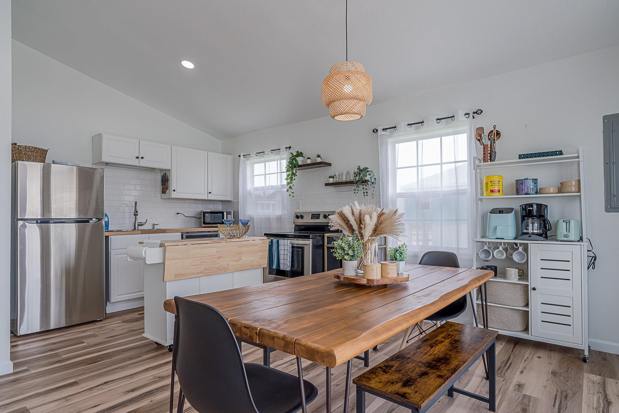 Kitchen and dining area with white cabinetry, stainless appliances, and a large wooden table.