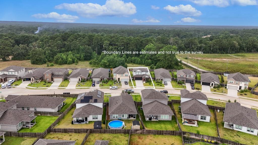 Aerial view of a home outlined in a subdivision beside a wooded area.