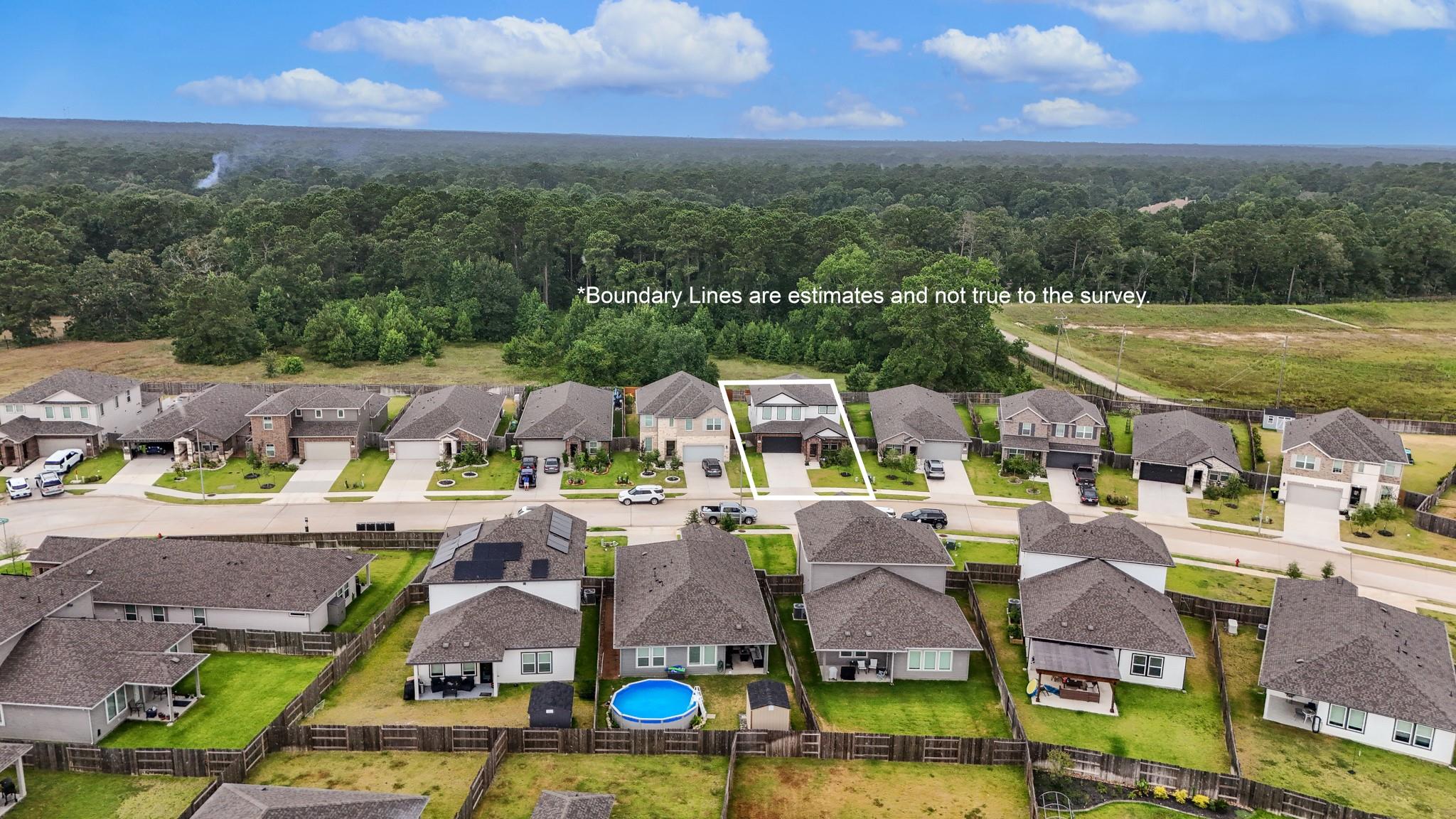 Aerial view of the outlined home lot, neighboring houses, and wooded area beyond.