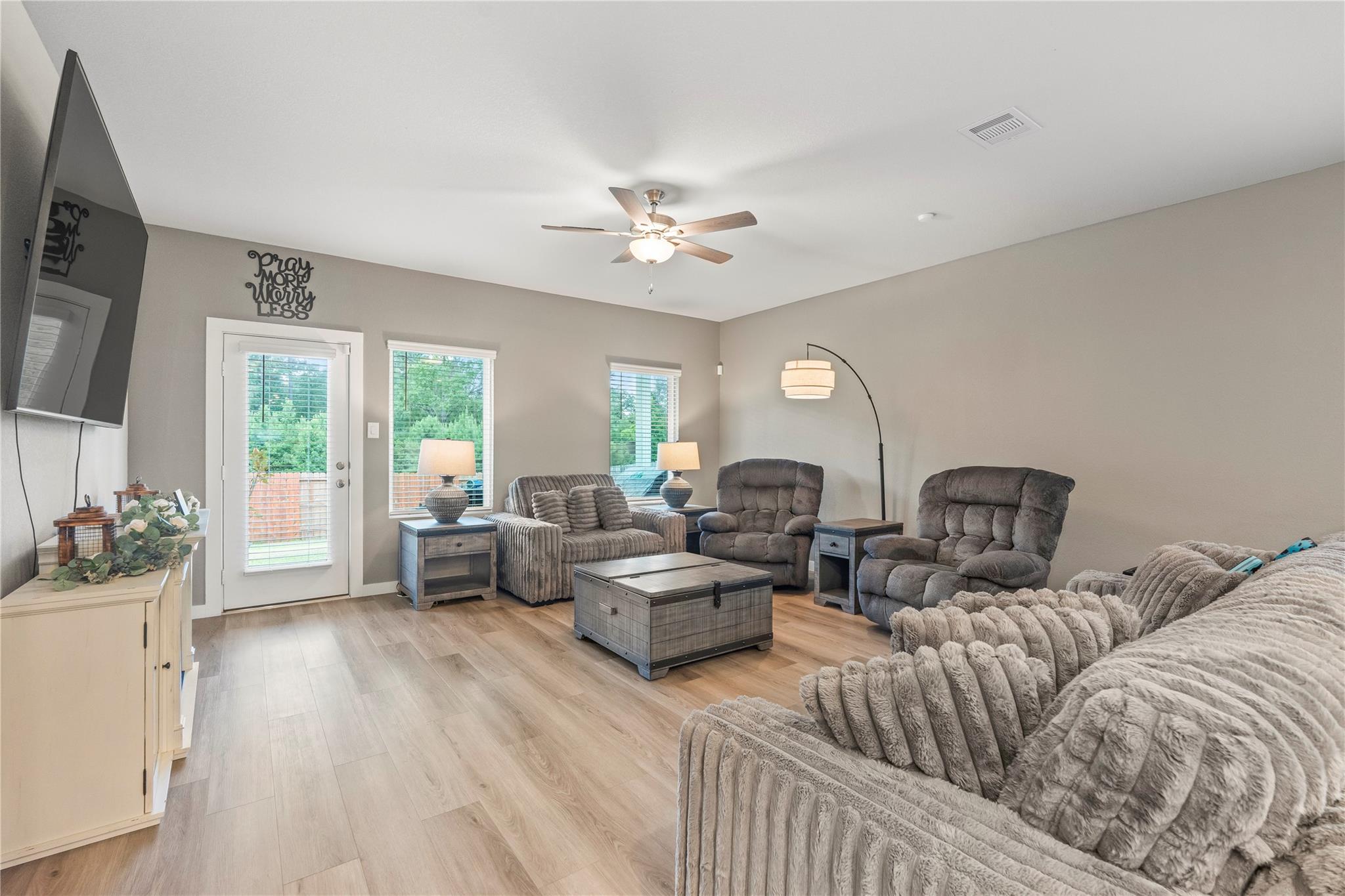Furnished living room with gray recliners, a metal-trimmed coffee table, and windows overlooking greenery.