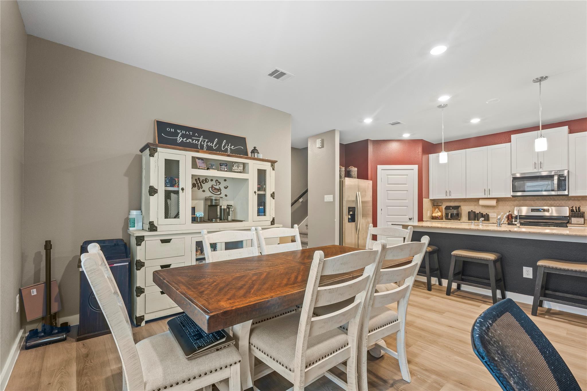 Open-plan kitchen and dining area with a dark wood table, coffee bar hutch, and white cabinetry.