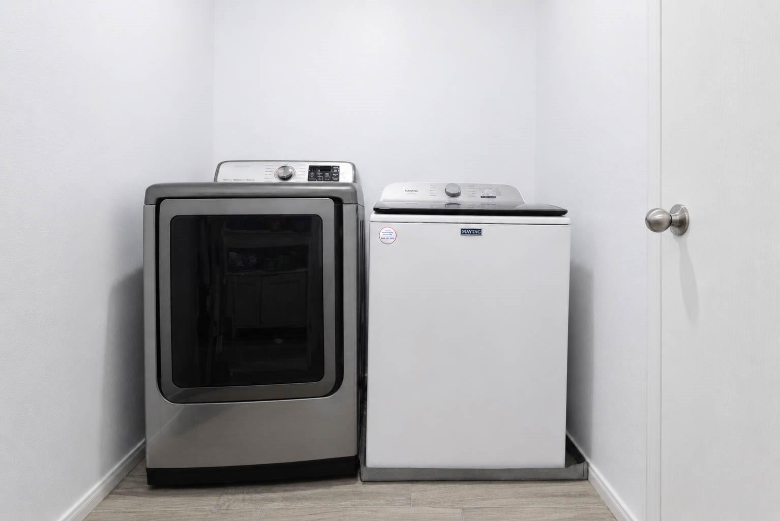 Laundry room with a stainless-steel front-load dryer beside a white top-load washer.