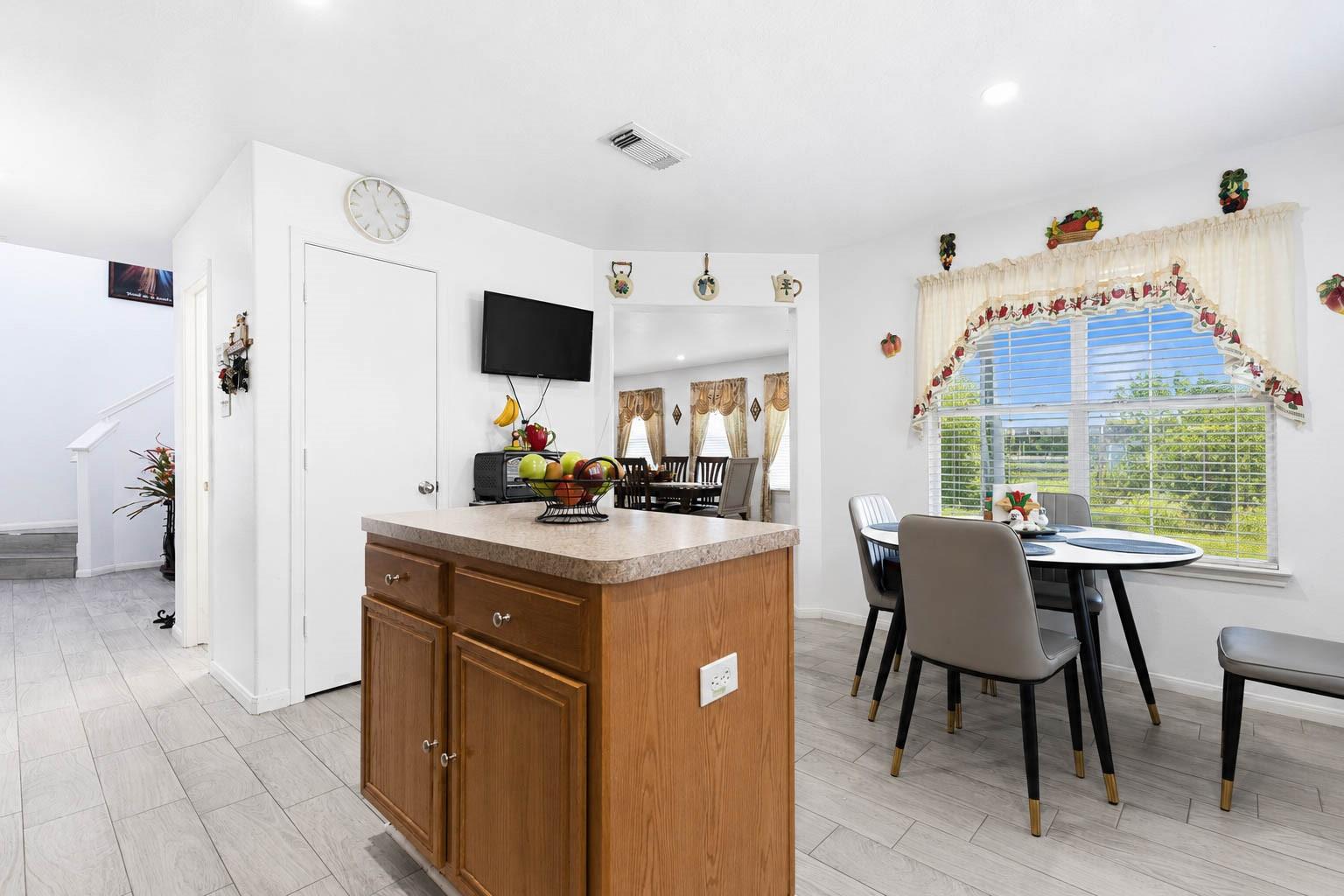 Kitchen island and dining table beside a large window with blinds.