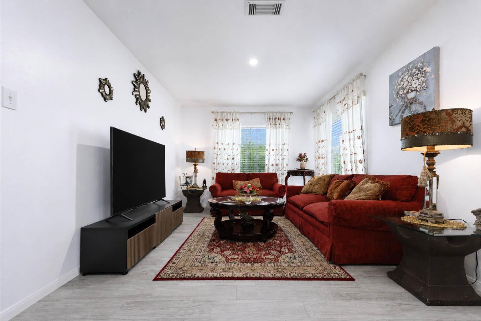 Living room with red sofas, a large television, and a patterned area rug.