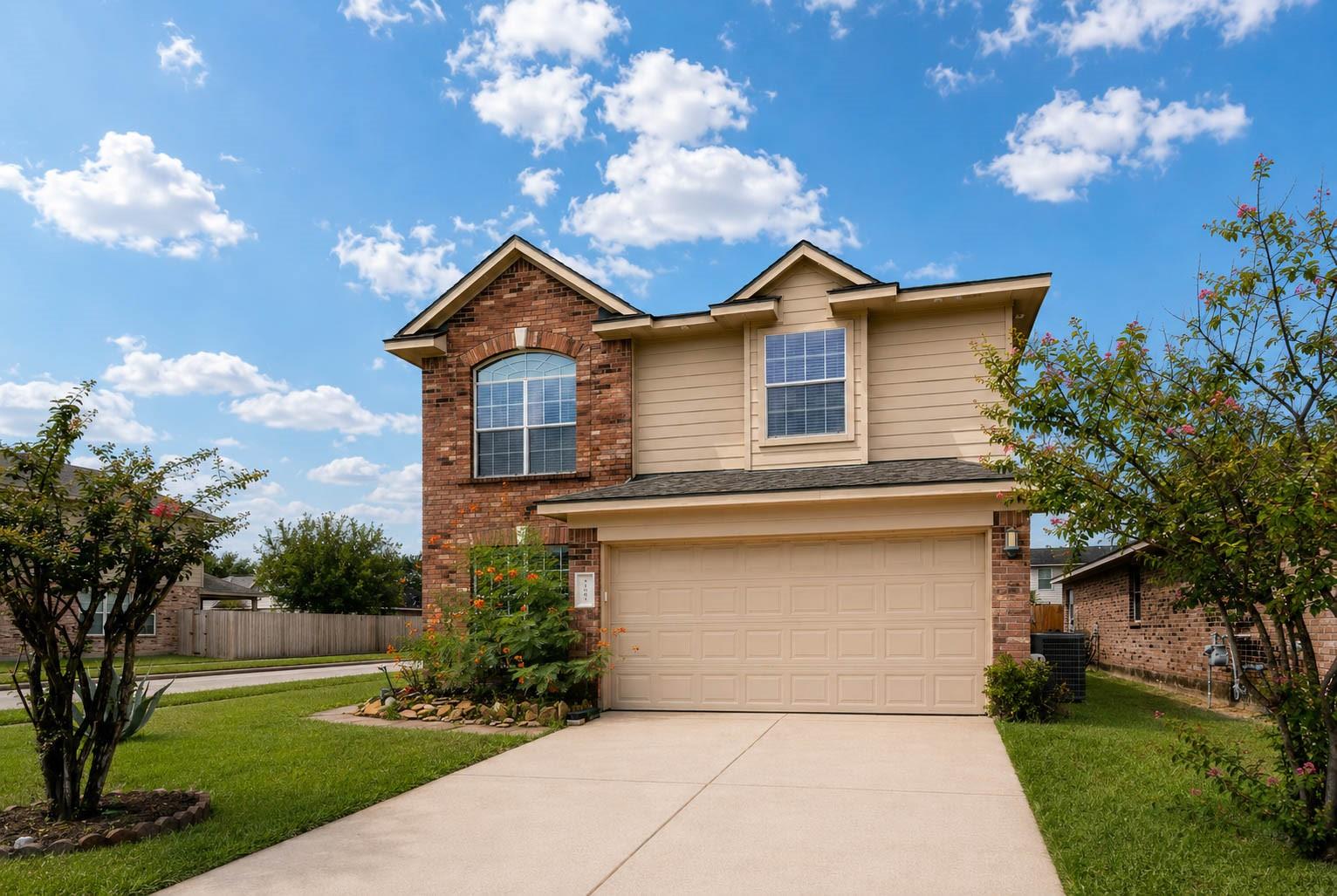 Two-story brick-and-beige house with an attached double garage and landscaped front yard.