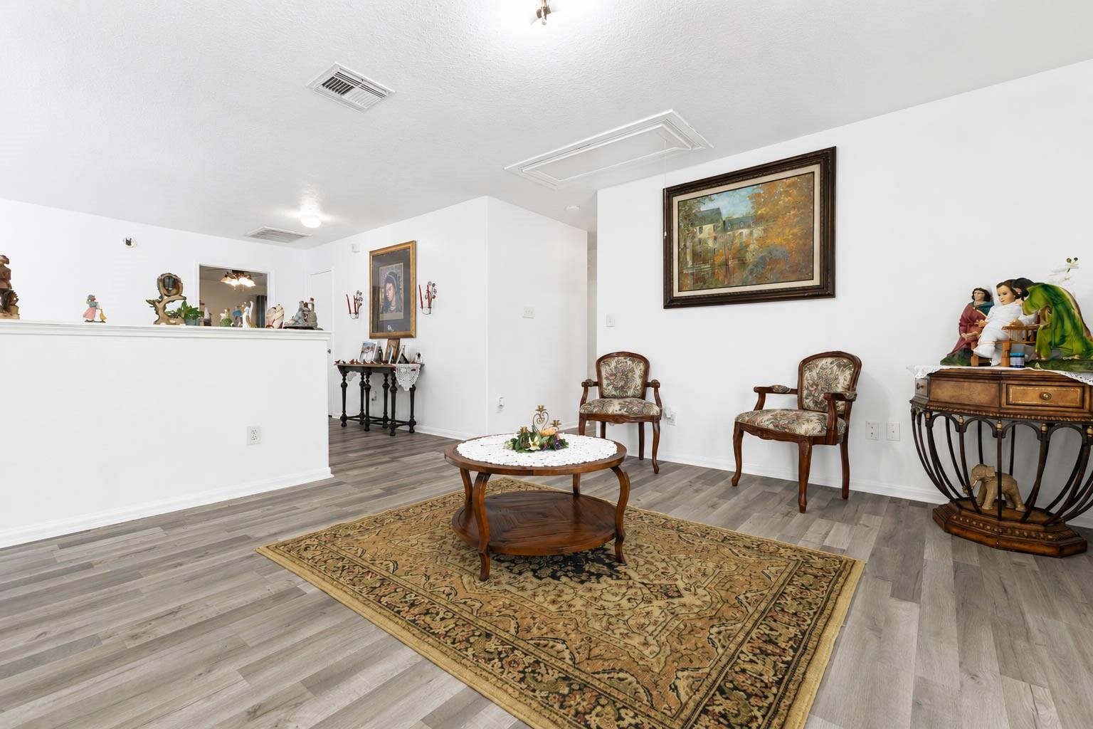 Furnished living room with a patterned rug, round wooden coffee table, and two upholstered armchairs.