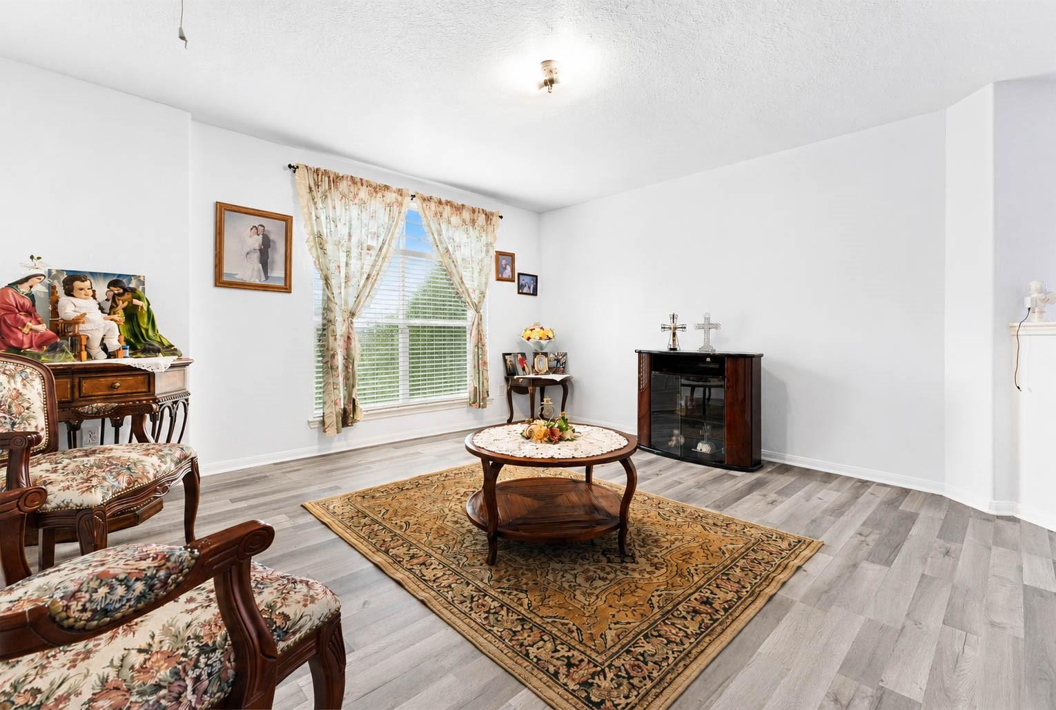 Living room with floral chairs, a patterned rug, and a curtained window.