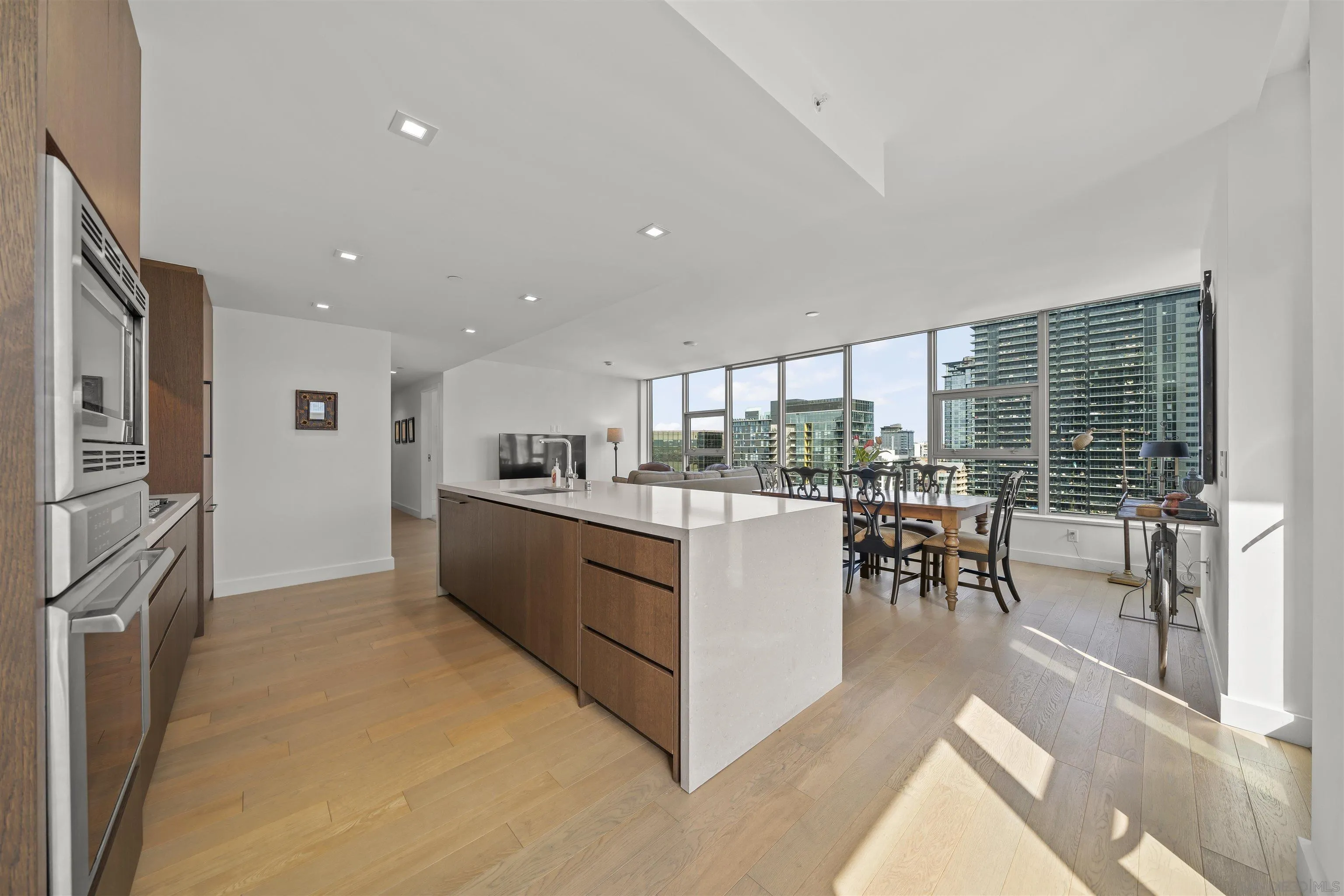 Open-plan condo kitchen with a white waterfall island and high-rise city views.