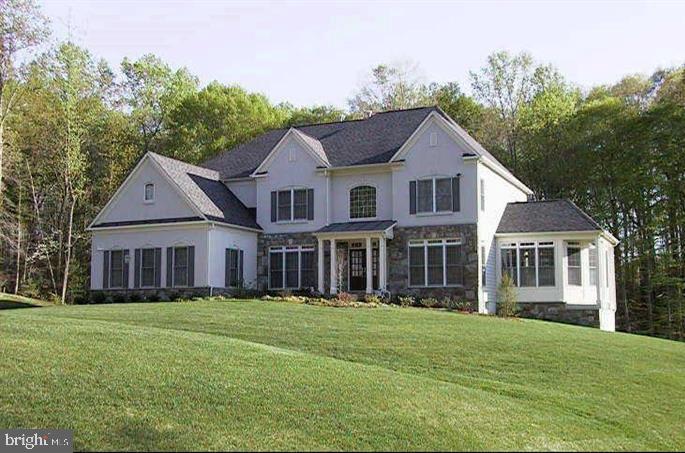 Two-story white house with dark gabled roofs, a front porch, and a sunroom behind a broad lawn.
