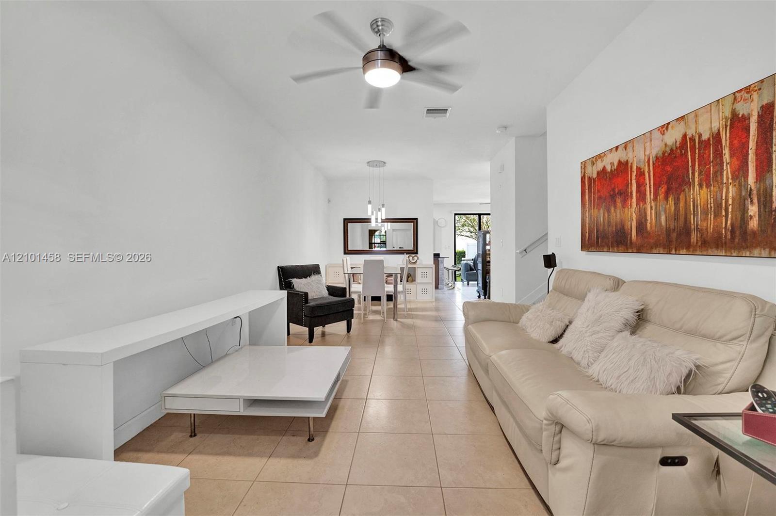 Living room with a cream sofa, white coffee table, and dining area beyond.