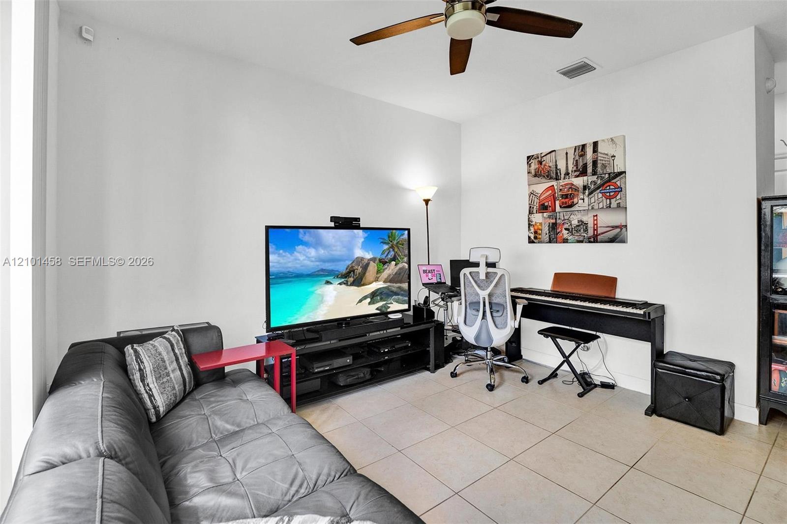 Furnished living room with a gray leather sofa, television, and digital piano.