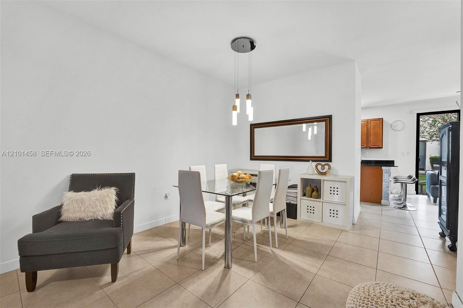 Furnished dining room with a glass-top table, white chairs, and a large framed mirror.