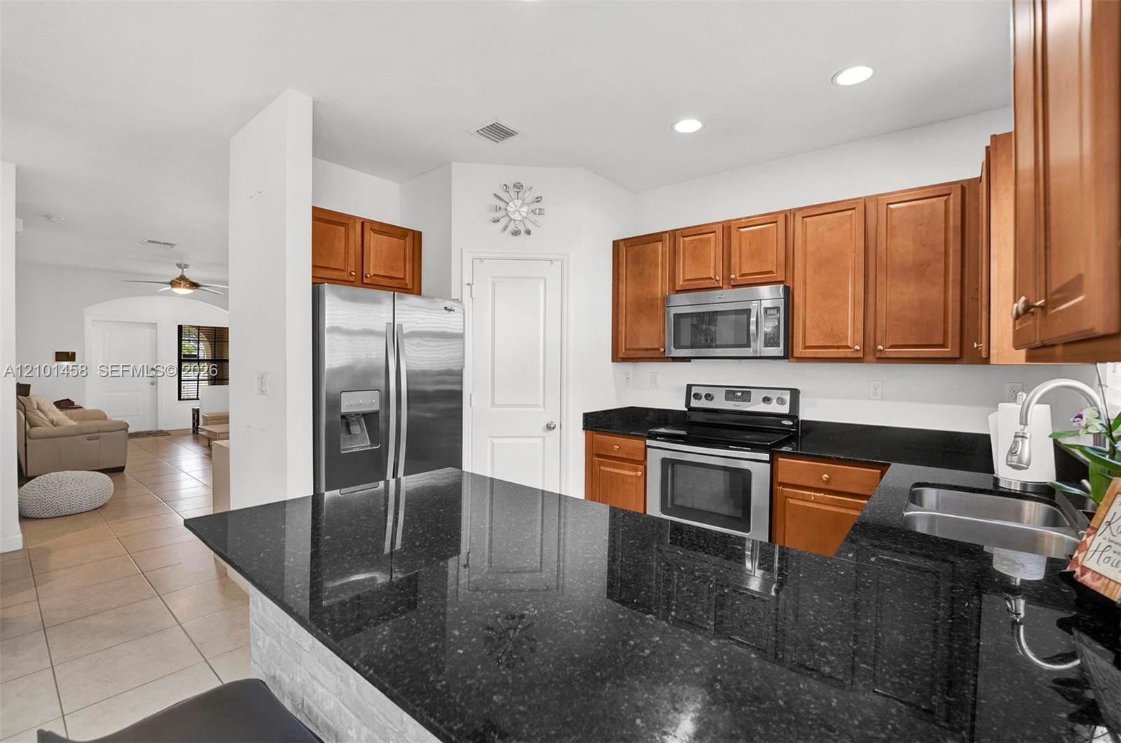 Kitchen with a black granite island, warm wood cabinets, and stainless steel appliances.