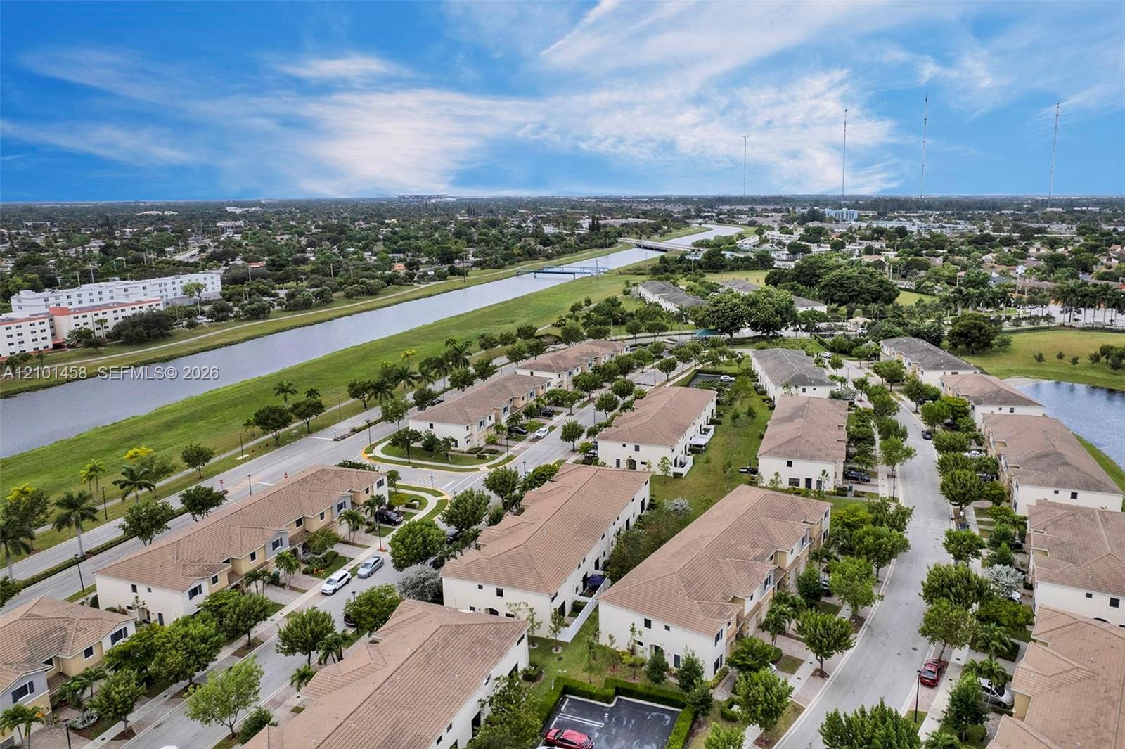 Aerial view of homes beside a canal, with green banks and bridges.