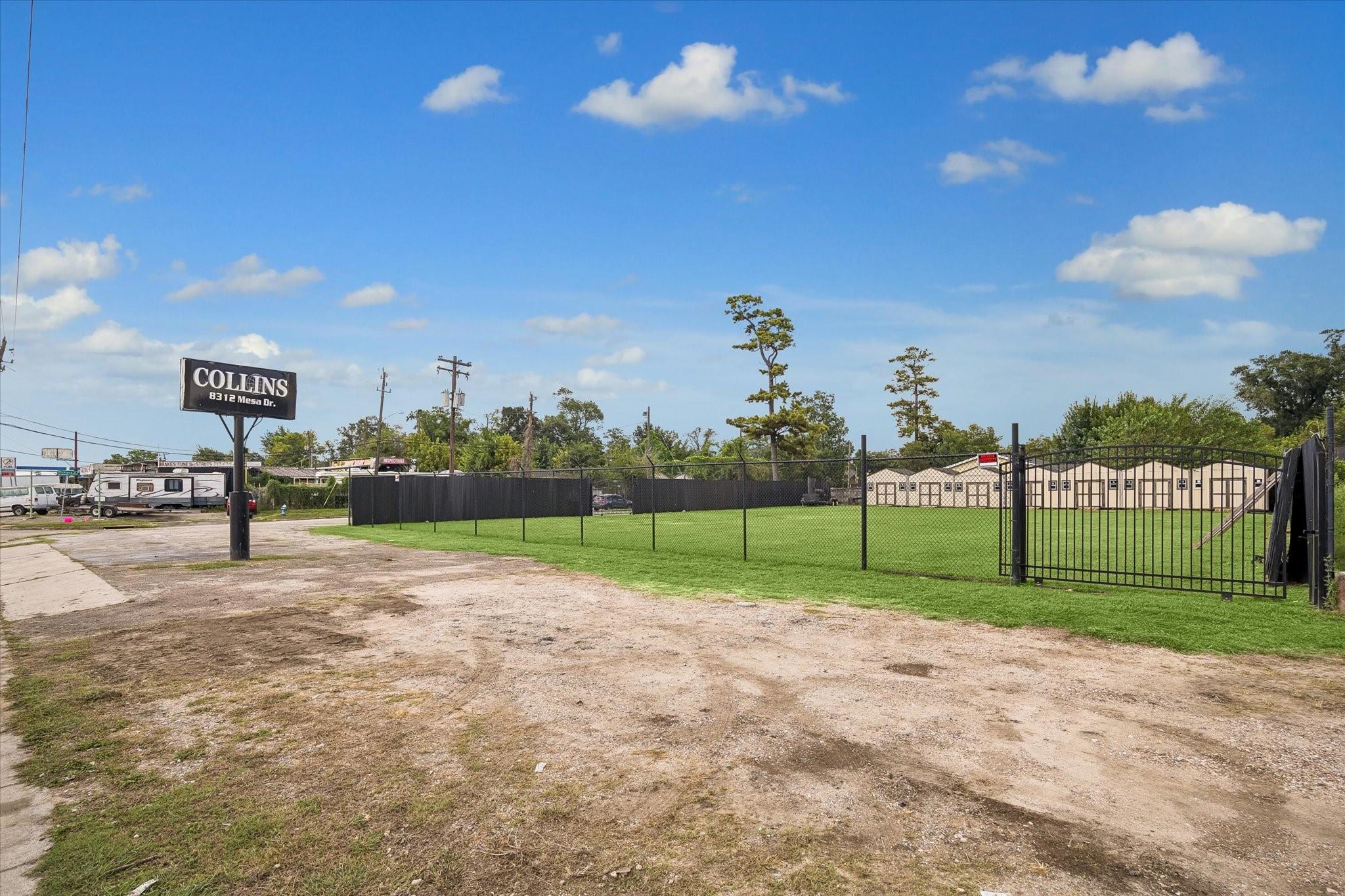 Fenced commercial lot with grassy yard, gravel frontage, and modular buildings.