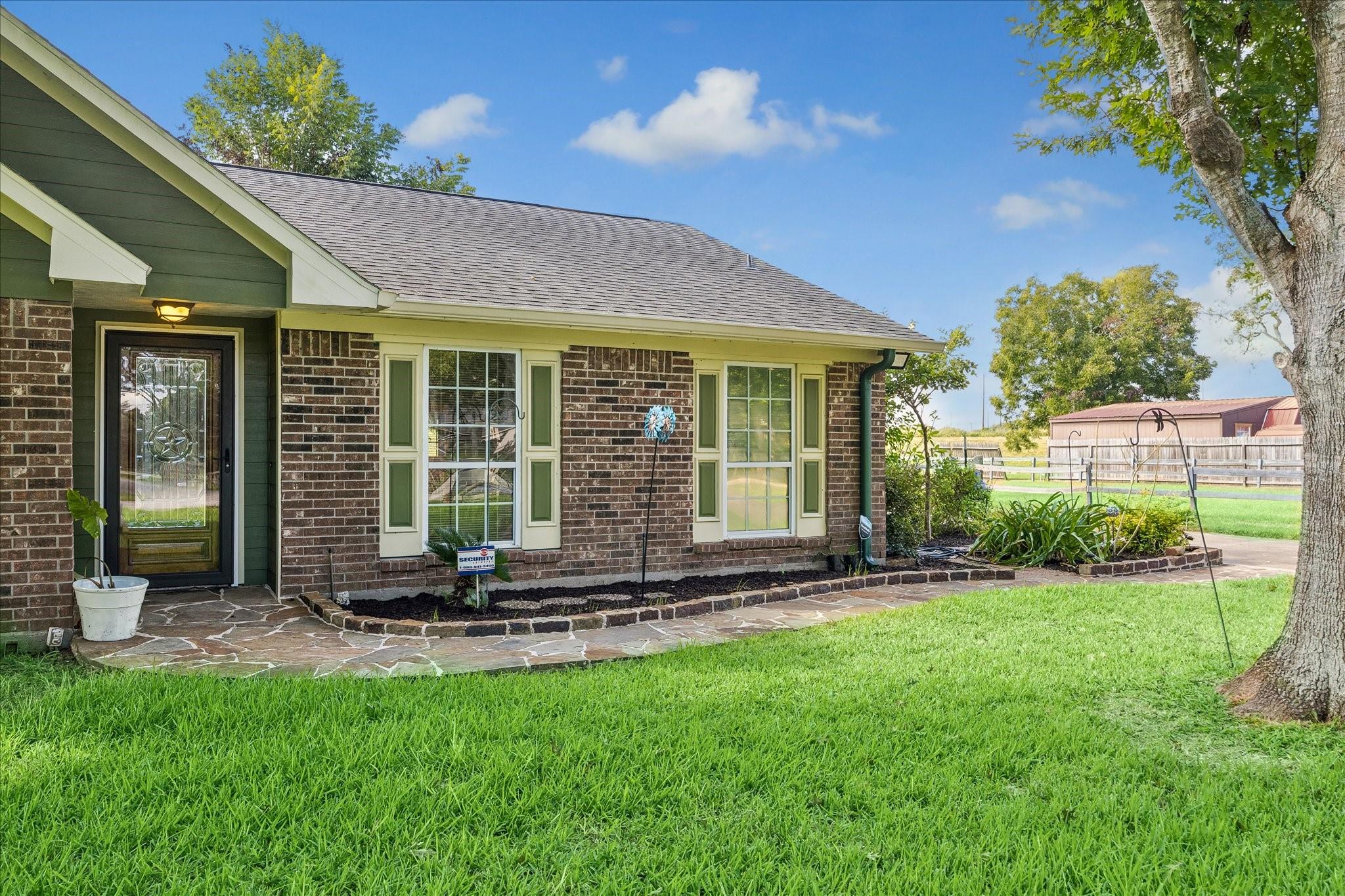 Brick house with green siding, a stone walkway, and a broad lawn.