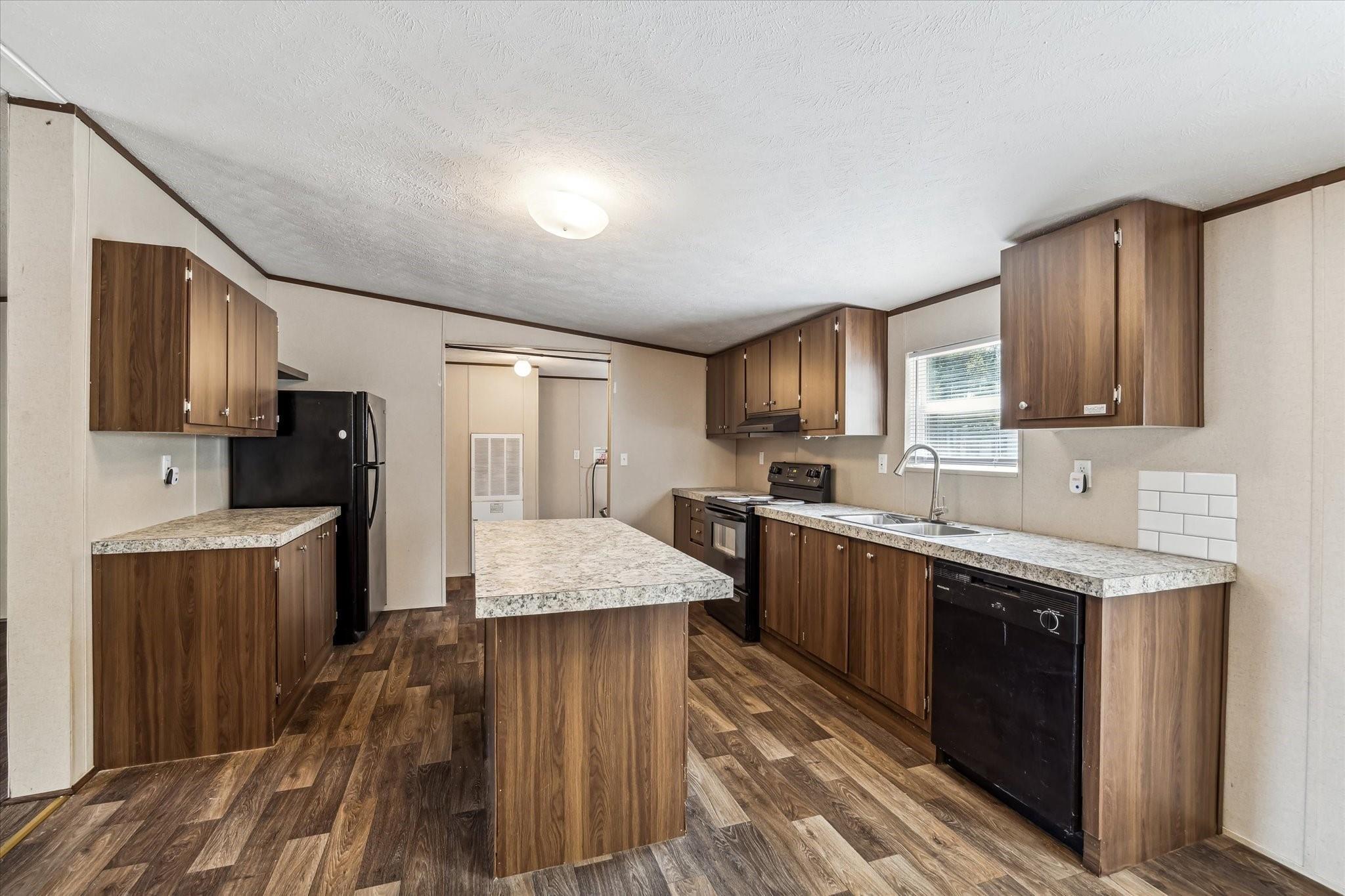 Kitchen with a central island, dark wood cabinets, and black appliances.