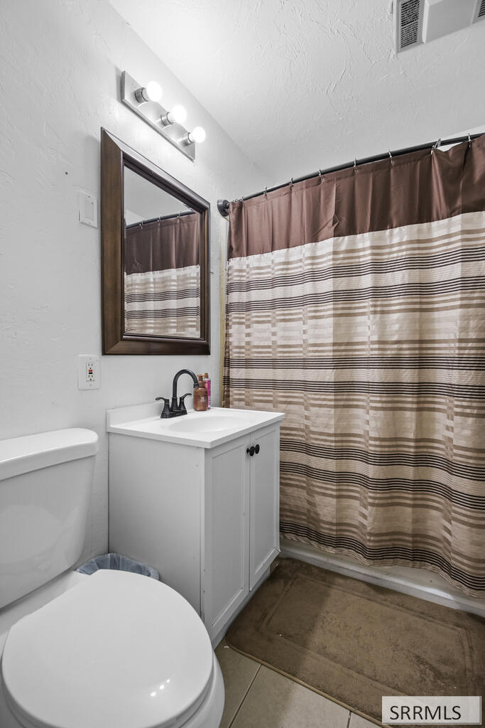 Bathroom with white vanity, toilet, dark-framed mirror, and striped shower curtain.