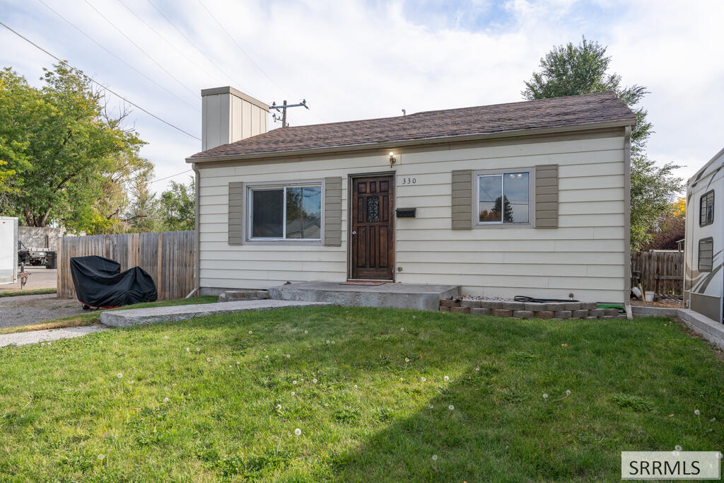 Single-story house with light siding, a dark front door, and a broad lawn.