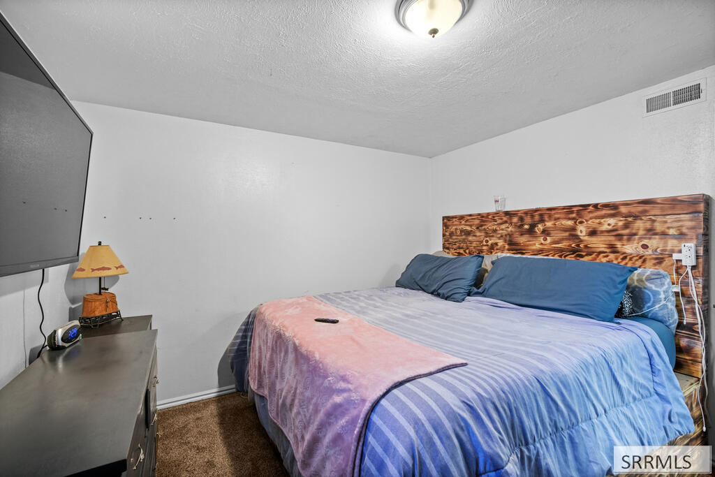Bedroom with blue and pink bedding and a rustic wood headboard