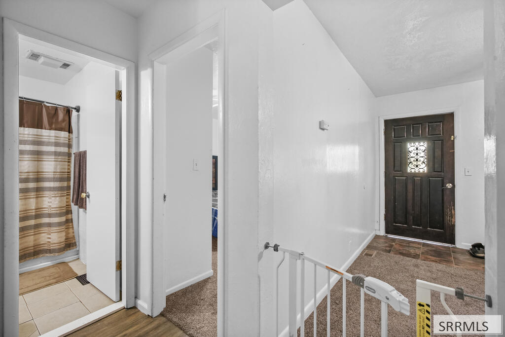 Entry hall with a dark front door, child safety gate, and open bathroom doorway.