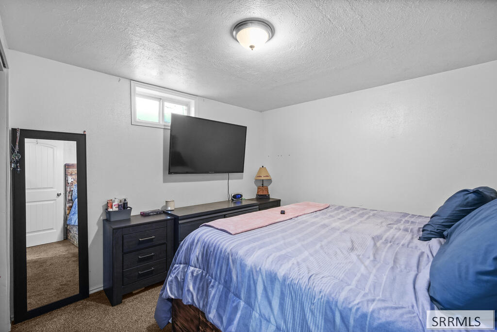 Bedroom with a blue bedspread, dark dresser, and wall-mounted television.