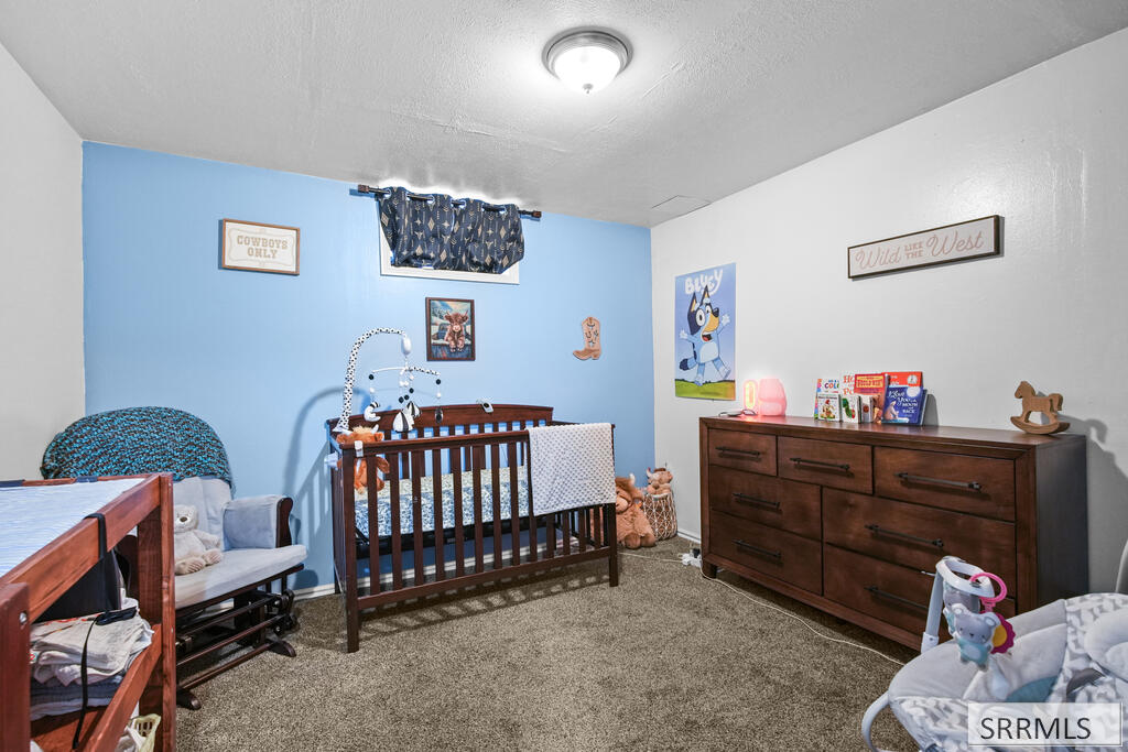 Furnished nursery with a dark wood crib, dresser, and blue walls decorated with children's art.