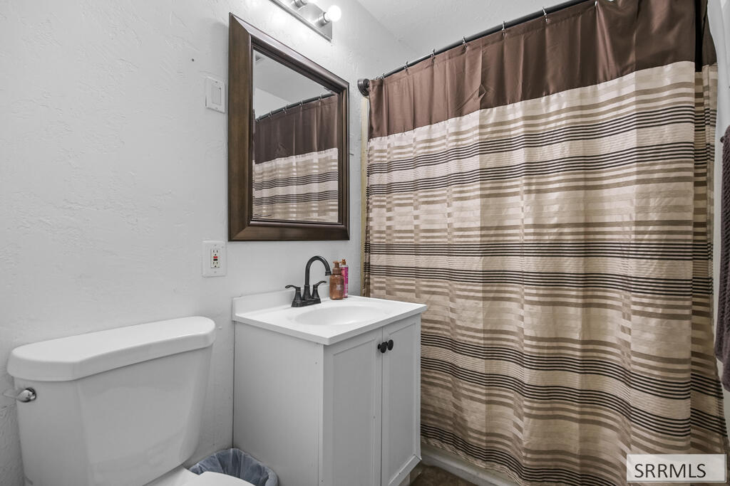 Bathroom with a white vanity, toilet, and brown-and-beige striped shower curtain.