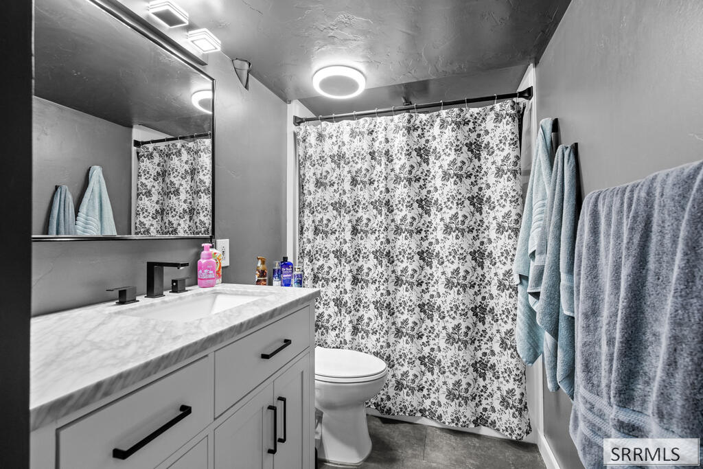 Bathroom with a white vanity, floral shower curtain, and towels hanging beside the shower.