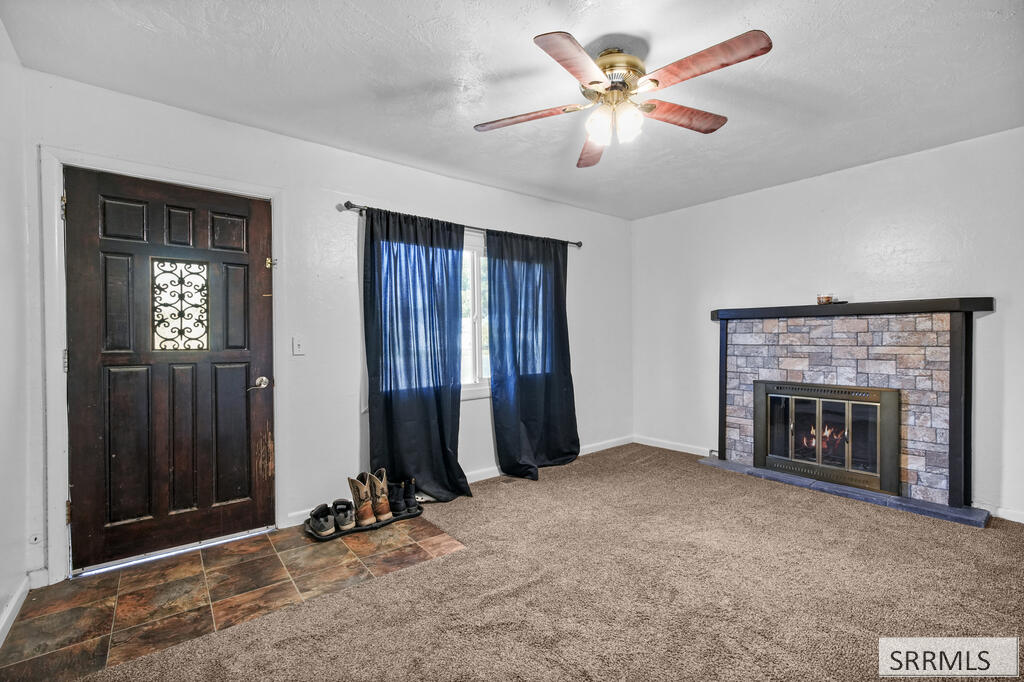 Living room with a stone fireplace, blue curtains, and dark wood entry door.