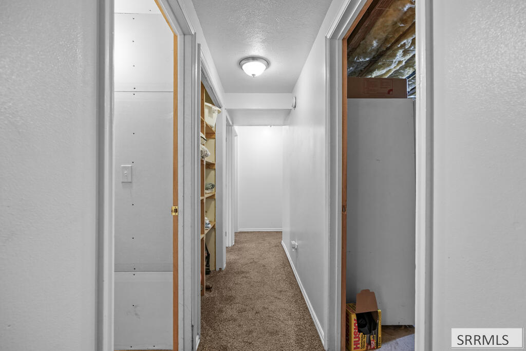 Carpeted hallway with open storage closets on both sides.