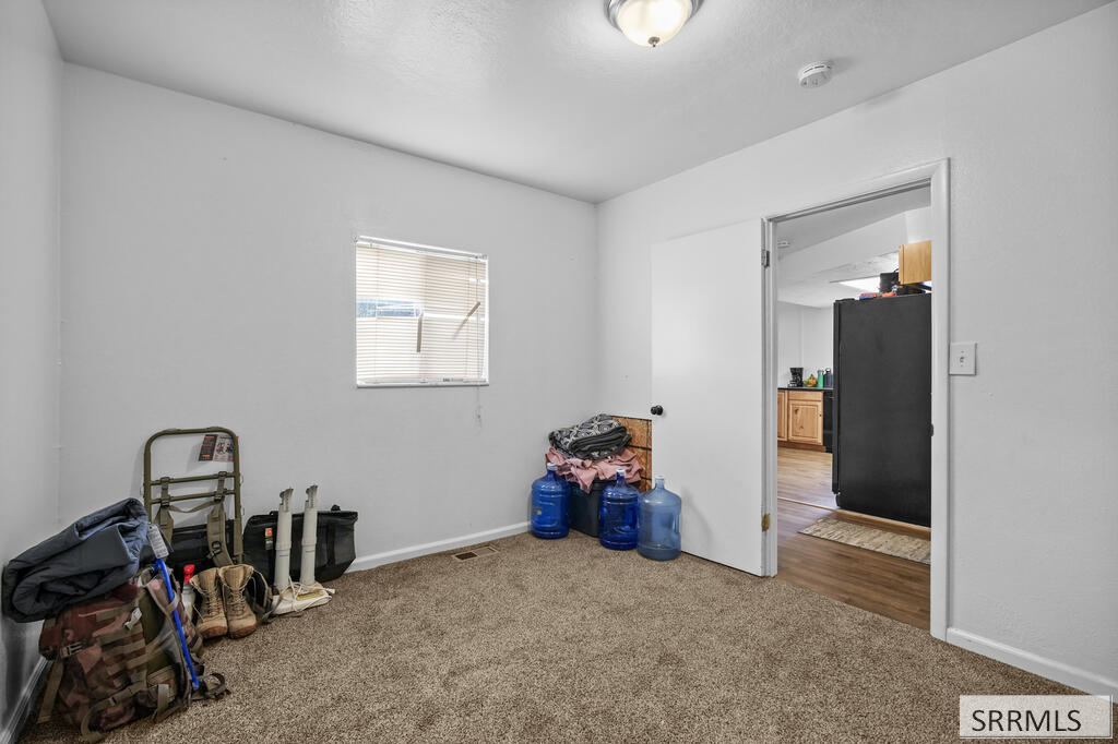 Carpeted room with a small window and an open doorway to a kitchen.