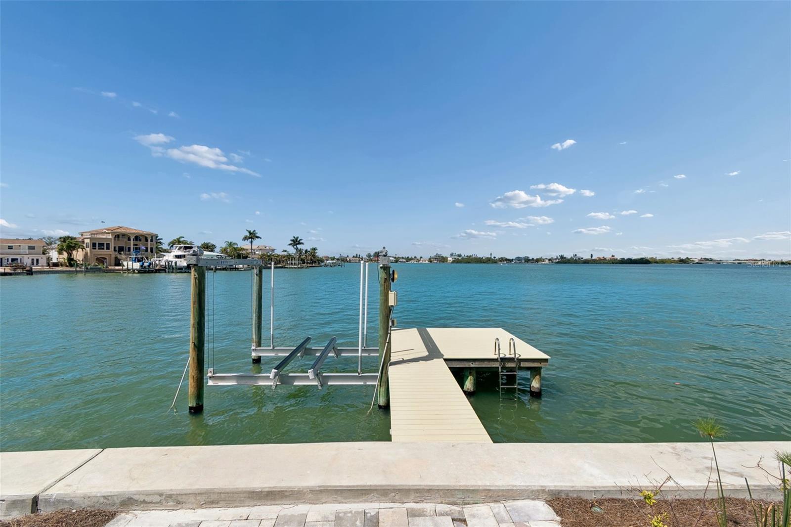 Waterfront dock with a boat lift and swimming ladder extending into the bay.