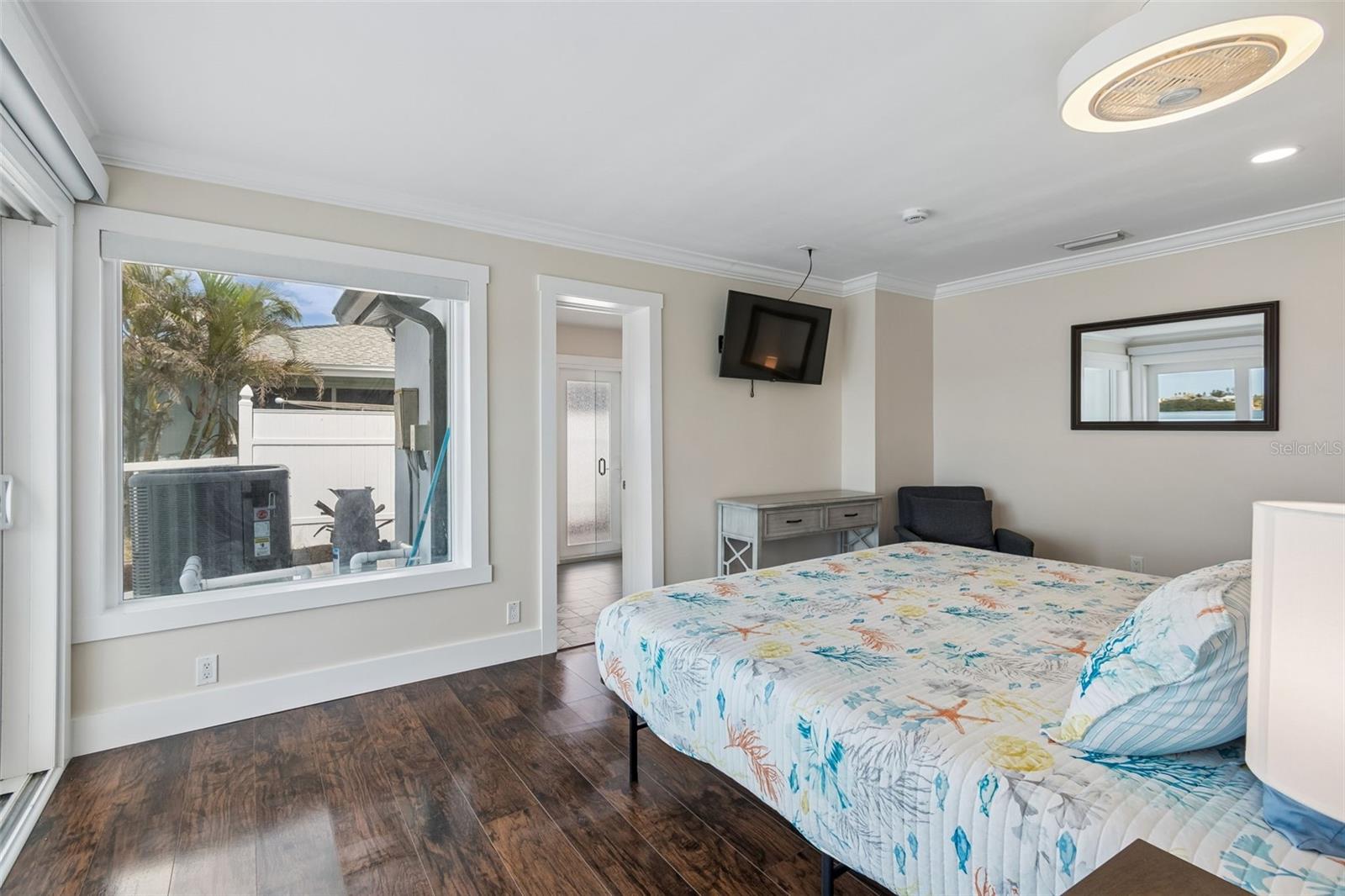 Bedroom with tropical-print bedding, dark tile floors, a ceiling fan, and a wide window.